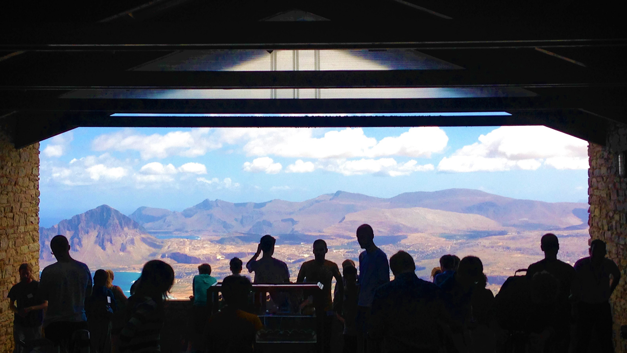 Grupo de pessoas apreciando a vista de montanhas e uma praia