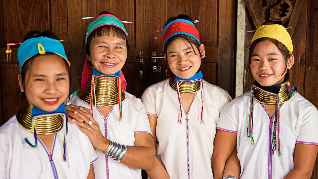 Quatro mulheres da tribo Padaung, da Tailândia usando anéis de cobre no pescoço em sinal de beleza.