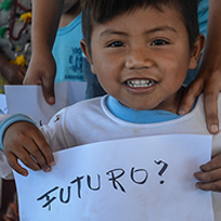 Foto de uma criança indígena segurando um papel escrito "Futuro?"