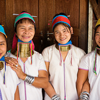 Quatro mulheres da tribo Padaung, da Tailândia usando anéis de cobre no pescoço em sinal de beleza.