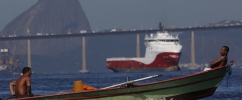 Dois homens em um pequeno barco na Baía de Guanabara com o Pão de Açúcar ao fundo