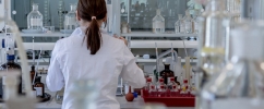 Pessoa com jaleco de cientista de costa em um laboratório